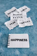 Happiness text on notepad with Fear Anxiety Stress and Burnout words next to Mental health text on torn sticky taped page, psychology concept