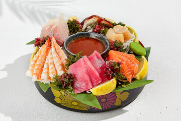 Sashimi set from raw seafood: salmon, tuna, eel, perch, shrimps, sea scallop. Traditional japanesse dish - sashimi on white background. Fresh delicacy on ice with lemon, ginger and sauce. - obrazy, fototapety, plakaty