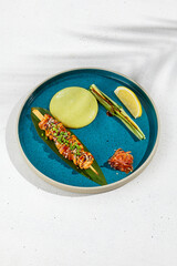 Squid yakitori in ceramic dish on white background. Japanese skewered squid with wasabi sauce. Grilled kalmar on bamboo skewer in asian style. Food menu for izakaya. Summer pan asian menu. © Ryzhkov