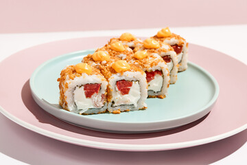 Alternative maki roll with chicken on coloured background. Sushi roll with chicken, cheese and tomato inside, bread crumbs outside. Maki sushi in minimal style. Japanese menu concept.