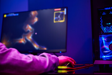 Teenager boy play computer video game in dark room, use neon colored rgb mechanical keyboard, workplace for cybersport gaming