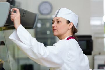 delicatessen worker checking the controls of the cabinet