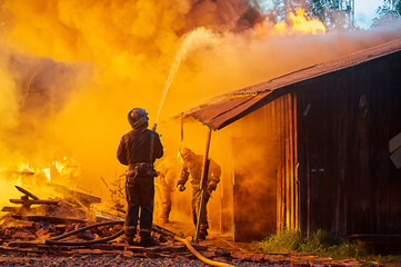 Obraz premium Firefighters extinguish a fire in a farm building