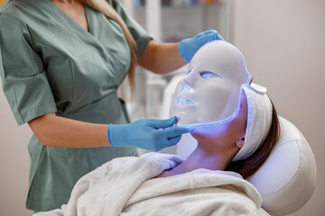 Cosmetic procedure with LED facial mask for female face. Photon therapy.