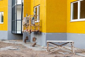 Professional construction cradle or gondola for construction work at height of a high-rise building. Industrial equipment for work at height.