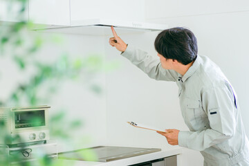 キッチンと作業着姿の男性（換気扇）
