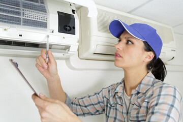 Fototapeta na wymiar a young woman cleaning air conditioning system at home