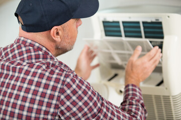 Naklejka na ściany i meble portrait of a man adjusting air conditioning system