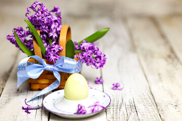 Obraz na płótnie Canvas Easter composition with egg and egg cup with Hyacinth spring flowers on wooden background