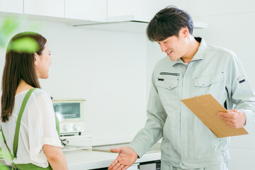 Obraz premium キッチンで話す作業着姿の男性と女性（食洗機） 