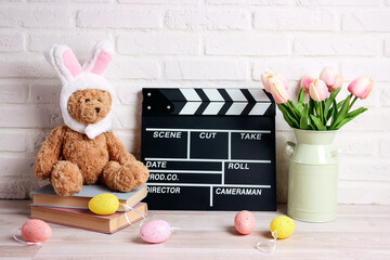 Movie clapper board with Easter decorations against a white brick wall. Cinema for the spring holidays.