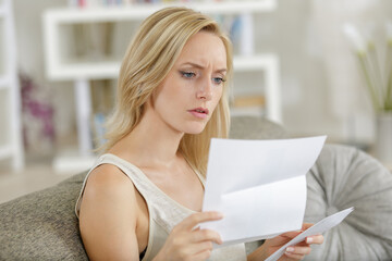 woman on sofa looking upset while reading letter