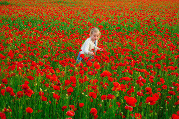 Child girl resting in a poppies spring meadow. Kids play in the field with poppy flowers. Little girl have fun and enjoy the freedom outdoor. Spring flower blossom meadow background.