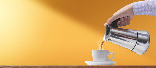 Woman pouring hot coffee in a cup