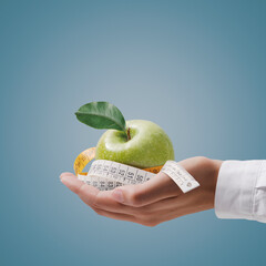 Nutritionist holding a tape measure and an apple