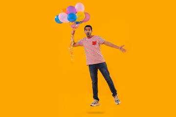 Happy young man flying with air balloons