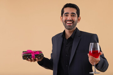 Portrait of happy businessman holding gift and wine glass in hands