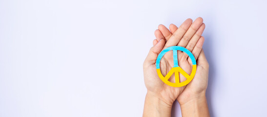 Support for Ukraine in the war with Russia, Hands holding symbol of peace with flag of Ukraine. Pray, No war, stop war, stand with Ukraine and Nuclear Disarmament
