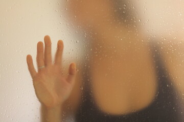 View of an unrecognizable woman placing her hand behind a frosted glass