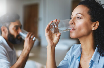 Cool, clean and refreshing. Shot of a couple drinking glasses of water together at home.