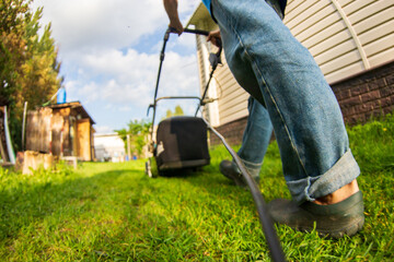 Happy retired senior person mows a lawn in his garden with a lawnmower. Garden work.