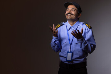 Indian Security guard wearing a security uniform over isolated dark background gesturing hand and...