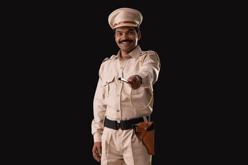 Portrait of an Indian policeman pointing with baton