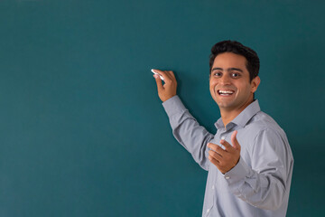 School teacher writing on blackboard while teaching in classroom