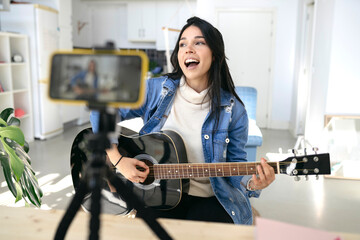 influential young woman playing guitar during podcast or live video broadcast for the audience from...