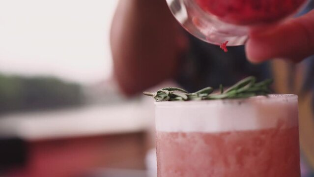 Professional bartenders prepare customers alcoholic cocktails with rosemary ice cubes at the cozy bar. on this beach