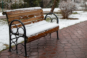 Benches with snow on the city park in snowy weather.