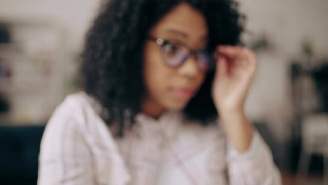 Black curly-haired woman working on laptop from home, freelance, part-time job