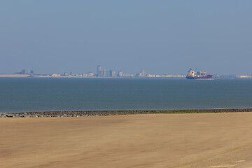 Fototapeta na wymiar Ship traffic entering the mouth of the Scheldt with the contours of Vlissingen in a far distance