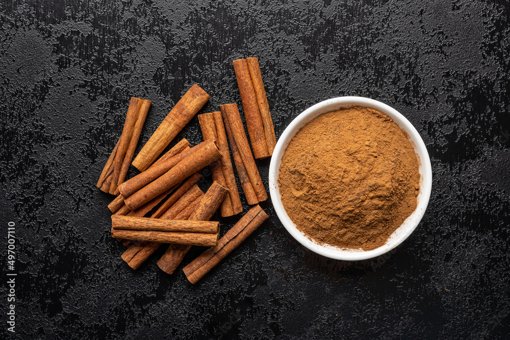 Wall mural dry cinnamon sticks and cinnamon powder on black table. cinnamon spice.