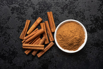 Dry cinnamon sticks and cinnamon powder on black table. Cinnamon spice.