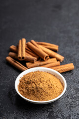Dry cinnamon sticks and cinnamon powder on black table. Cinnamon spice.
