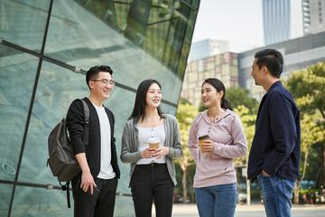 group of young asian adults men and women standing talking on street
