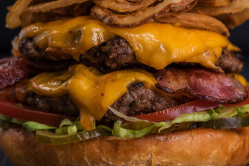 Giant beef burger with frankfurters on a black background
