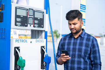 customer at petrol pump using mobile phone - concept of using social media, technology and...