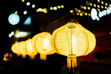 A row of yellow lanterns at night against a blurred background.