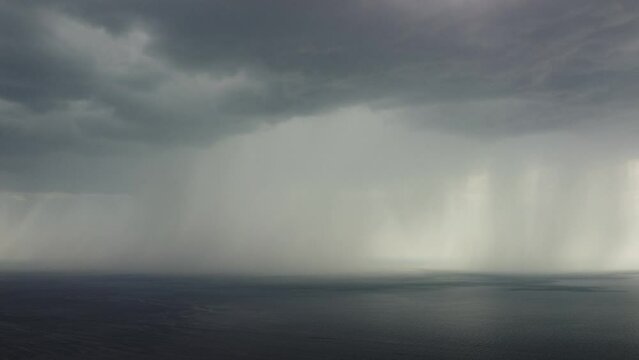 Aerial view footage of rain clouds over sea ocean Black clouds in bad weather day over sea surface High angle view nature view. Apocalypse. Storm Large freight dark gloomy rain clouds over a calm sea.