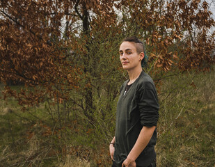 Naklejka na ściany i meble Outdoor portrait of young and confident white nonbinary person against fall background
