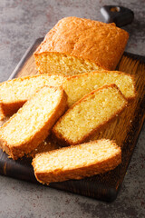 Regular loaf of madeira pound cake on a wooden cutting board on the table. Vertical