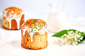 Easter cake decorated with white sugar icing and colored confectionery dragee and lily of the valley on a white background.