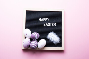 Happy easter. Easter eggs with a feather on a pink background.