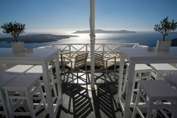 Breathtaking view from an outdoor bar with chairs and tables in Fira Santorini