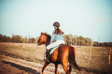 Young woman athlete rides a horse. Jumping training in the spring in the field.