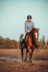 Young woman athlete rides a horse. Jumping training in the spring in the field.