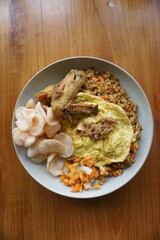 proper breakfast menu. a plate of fried rice topped with fried chicken, omelette and crackers.