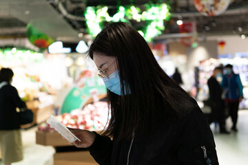Asian woman in supermarket wearing protective medical mask during Omicron, Covid-19 outbreak.